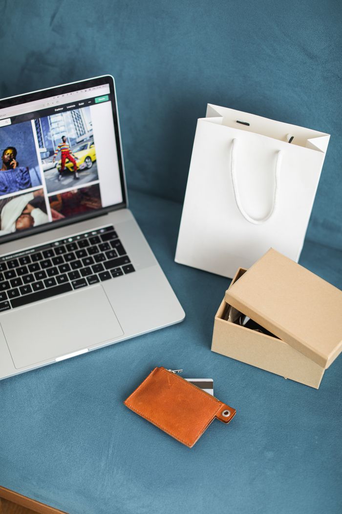 The Art of Drawing Readers In: Your attractive post title goes here A high-angle view of online shopping items including a laptop, gift bags, and wallet on a blue surface.